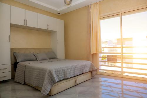 1 dormitorio con cama y ventana grande en Appartement vue sur piscine et sur mer en Taghazout