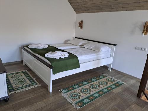 a bedroom with a white bed with a green blanket at PENSIUNEA CASTELANA in Racoşu de Jos