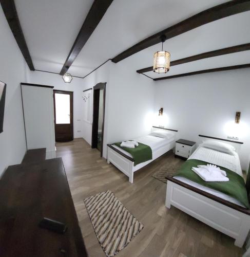 two beds in a room with white walls and wooden floors at PENSIUNEA CASTELANA in Racoşu de Jos