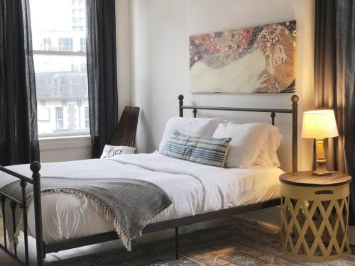 a bedroom with a bed and a lamp and a window at Airy and Bright on Broadway in Nashville