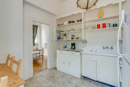 a kitchen with white cabinets and a sink and a table at Airy and Bright on Broadway in Nashville