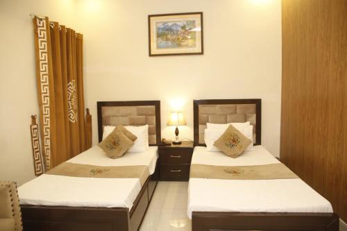 a bedroom with two beds and a night stand with a lamp at Park View Hotel Gulberg in Lahore