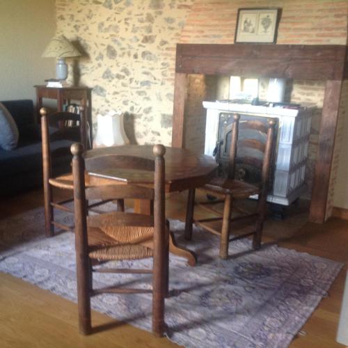 une salle à manger avec une table et des chaises et une cheminée dans l'établissement superbe petite maison de caractère dans le Cantal, à Maurs