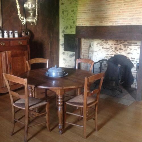 une table et des chaises en bois dans une pièce avec une cheminée dans l'établissement superbe petite maison de caractère dans le Cantal, à Maurs