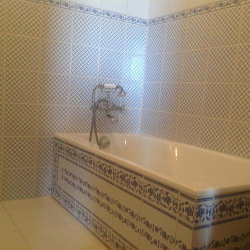 y baño con bañera y azulejos azules y blancos. en superbe petite maison de caractère dans le Cantal, en Maurs