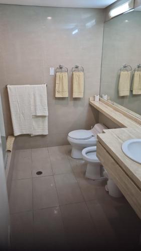 a bathroom with a toilet and a sink and towels at CCCT ApartaHotel Ccct in Caracas