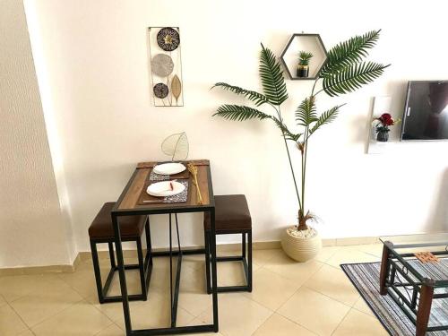 stół i krzesła w pokoju z rośliną w obiekcie New cozy apt. on the promenade w mieście Hurghada