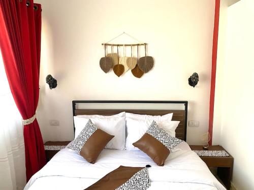 New cozy apt. on the promenade في الغردقة: غرفة نوم بسرير أبيض مع ستائر حمراء