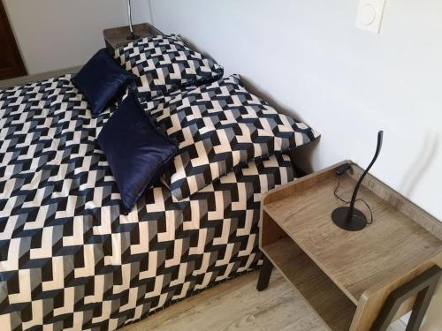 a bed with a black and white comforter and a wooden table at Le Plouf des Gargouilles in Onet le Château