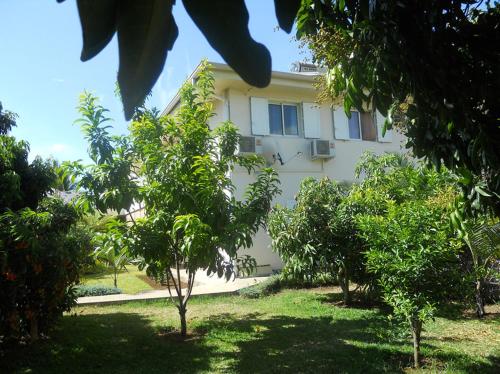 a white building with trees in front of it at Les Hibiscus de la Rivière in Saint-Louis