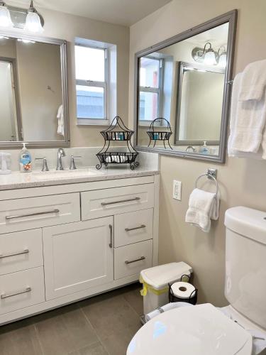 a bathroom with a toilet and a sink and mirrors at Harmonious Suites in North Miami Beach