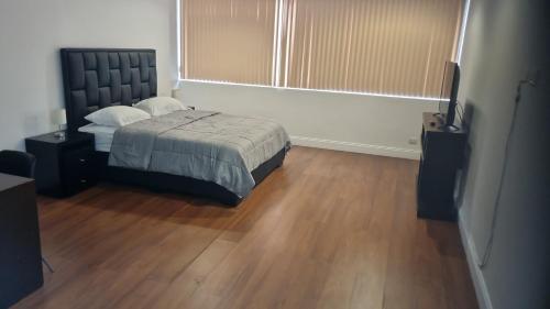 1 dormitorio con 1 cama y suelo de madera en CCCT ApartaHotel Ccct, en Caracas