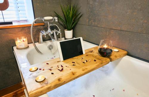 a bathroom with a bath tub with a glass of wine at Cosy Cumbrian cottage for your country escape in Brough