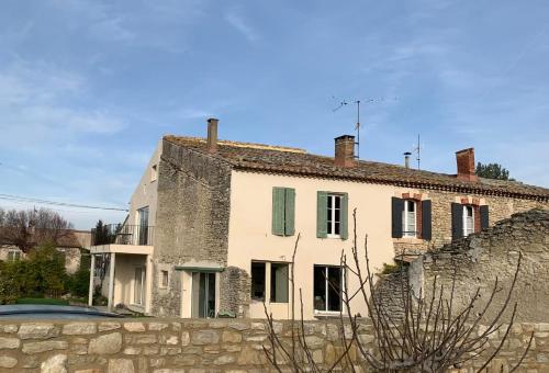 une maison blanche avec un mur en pierre devant elle dans l'établissement Clos du Cardinal avec piscine, à LʼIsle-sur-la-Sorgue