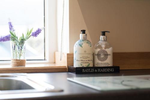 two bottles sitting on a counter next to a sink at Honeysuckle-Peaceful Scottish Cottage with Hot Tub in Airdrie