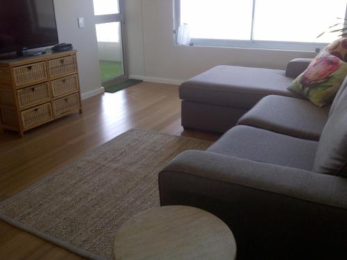 sala de estar con sofá y TV en Beachfront Apartment at Seaspray in Blouberg, en Bloubergstrand