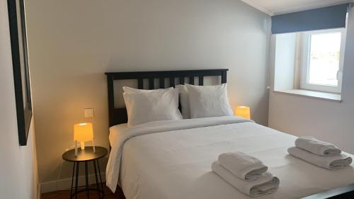 um quarto com uma grande cama branca com toalhas em SORIANO Place em Lisboa