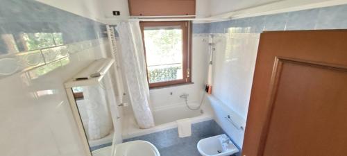 baño con aseo y lavabo y ventana en Spacious bright apartment near city center and Como lake with air conditioning, en Lecco