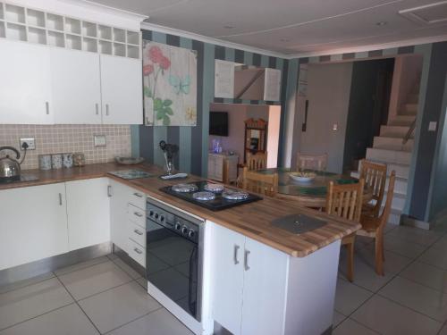 a kitchen with white cabinets and a wooden counter top at LISA VILLAGE in Bloemfontein