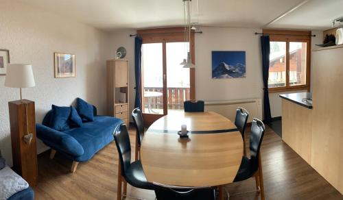 uma sala de estar com uma mesa de madeira e cadeiras azuis em Chrinnengletscher em Grindelwald