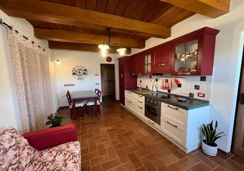 uma cozinha com armários vermelhos e uma mesa num quarto em Agriturismo La Valle Dimenticata em Urbania