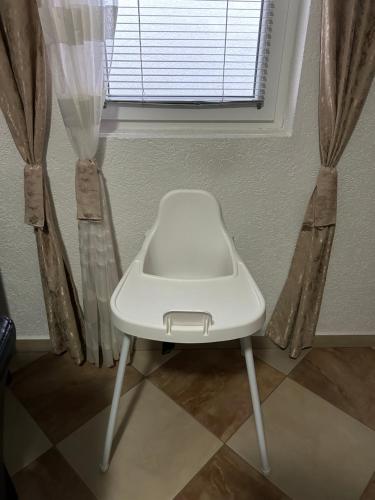 a white chair sitting in front of a window at Apartment Alpi in Peje