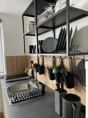 a kitchen with a sink and utensils on a shelf at Appartment 53qm im Architektenhaus - 2 Schlafzimmer mit Küche und Bad, nur 2min von A8 - ruhig und modern in Irschenberg