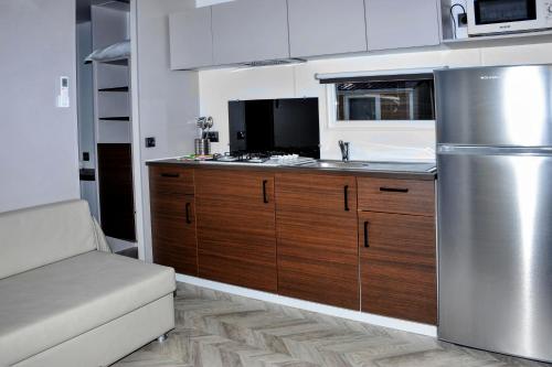 una cucina con armadi in legno e frigorifero in acciaio inossidabile di Baia Dei Micenei a Otranto