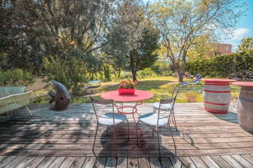 a red table and chairs on a wooden deck at Chambre d’Hôtes Neptune Wood in Arzens