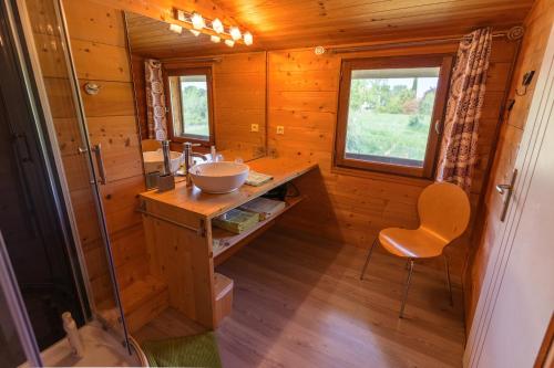 a bathroom with a sink and a chair in a cabin at Chambre d’Hôtes Neptune Wood in Arzens