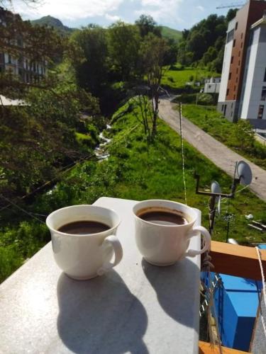 two cups of coffee sitting on top of a balcony at Orbi Palace Apartment in Bakuriani