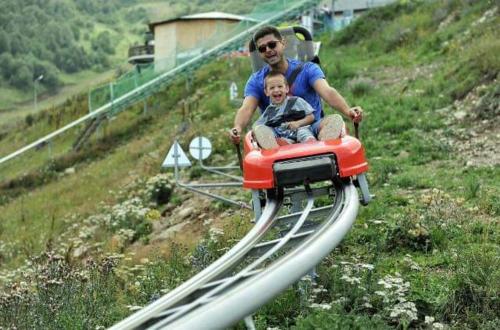 a man and a child riding on a roller coaster at Orbi Palace Apartment in Bakuriani