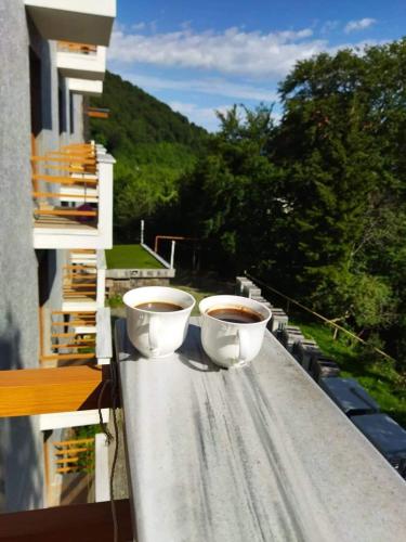two cups of coffee sitting on the ledge of a balcony at Orbi Palace Apartment in Bakuriani