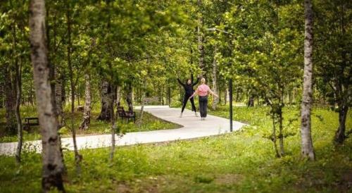 a woman walking down a path in a park with a skateboard at Orbi Palace Apartment in Bakuriani