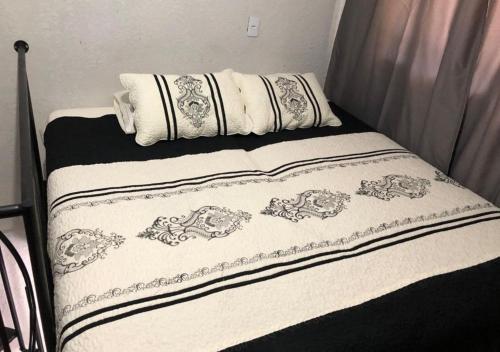 - un lit avec des draps et des oreillers en noir et blanc dans l'établissement Apartamento Loft encantador com patio, à Foz do Iguaçu