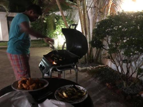 a man is cooking food on a grill at Sunset Beach Residence in Panadura