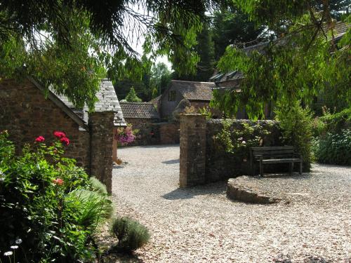 a garden with a bench and a stone wall at Duddings Country Cottages in Minehead