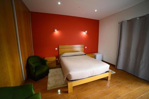 1 dormitorio con 1 cama y 1 silla verde en Funileiro, apartamentos e quartos en Amares