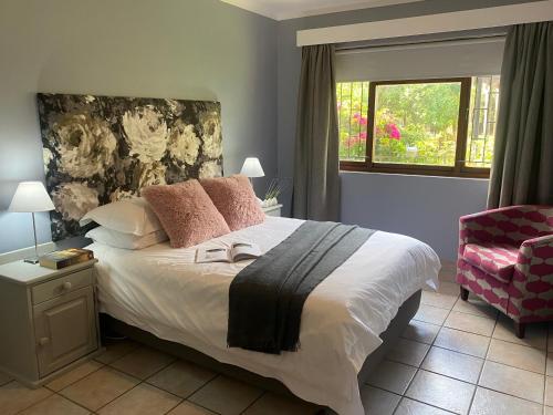 a bedroom with a bed and a chair and a window at Rooikrans Cottage in Groot Brak Rivier