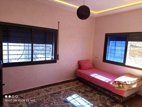 Pokój z czerwoną kanapą i dwoma oknami w obiekcie Super Chalet à Imouzzer kendar. w mieście Imouzzer Kandar