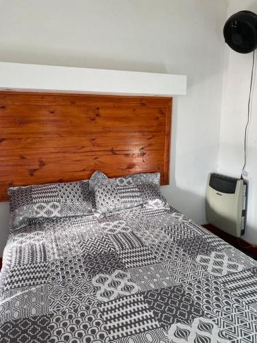 1 dormitorio con 1 cama con edredón blanco y negro en Departamento céntrico los cinco hermanos en Capilla del Monte