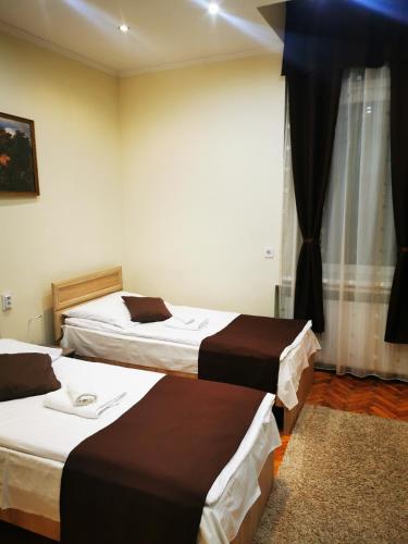 a hotel room with three beds and a window at Baross-hat 5 in Szolnok