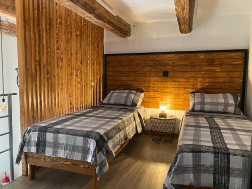 two beds in a room with wooden walls at Ta Serafina studio apartment with loft in Għajnsielem