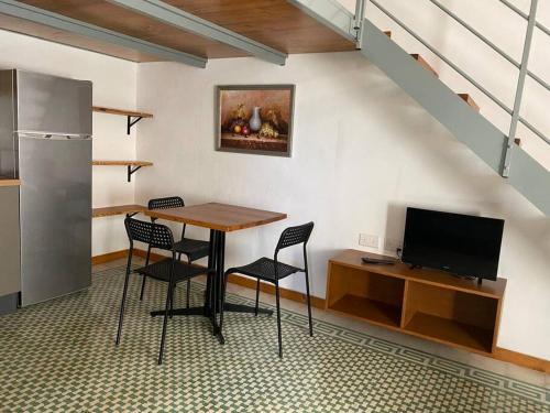 a dining room with a table and chairs and a tv at Ta Serafina studio apartment with loft in Għajnsielem