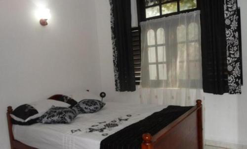 a bedroom with a bed with pillows and a window at Sunset Beach Residence in Panadura