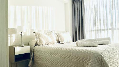 une chambre blanche avec un lit et une fenêtre dans l'établissement Apart Center Madryn, à Puerto Madryn