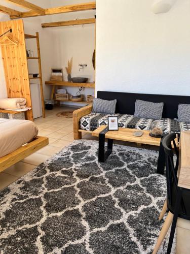 a room with two beds and a table and a rug at Spongia Apartments Kalymnos in Kalymnos