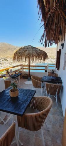 a patio with tables and chairs and an umbrella at Spongia Apartments Kalymnos in Kalymnos