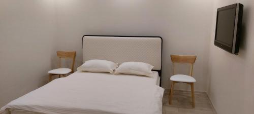 a bedroom with a bed with two chairs and a tv at Подобово ЖК Центральний вул.Нове Шосе, 8А in Bucha