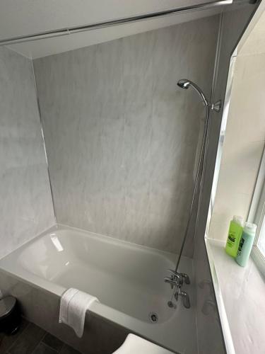 a bath tub in a bathroom with a mirror at Lovely Spacious 3 bedrooms house in Kingshurst